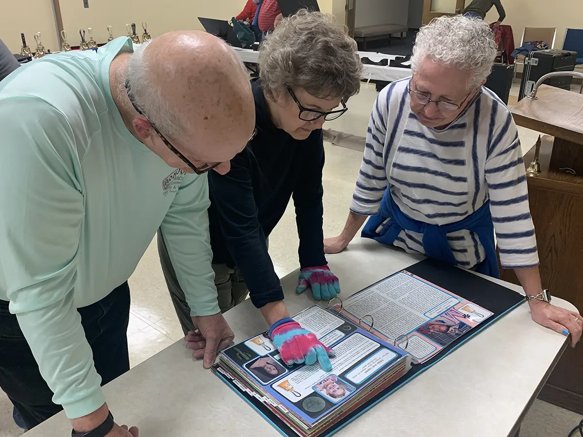 Three people looking at a scrapbook